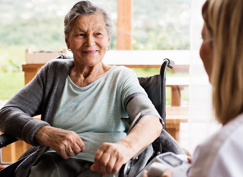 Image shows woman in wheelchair having her blood pressure checked