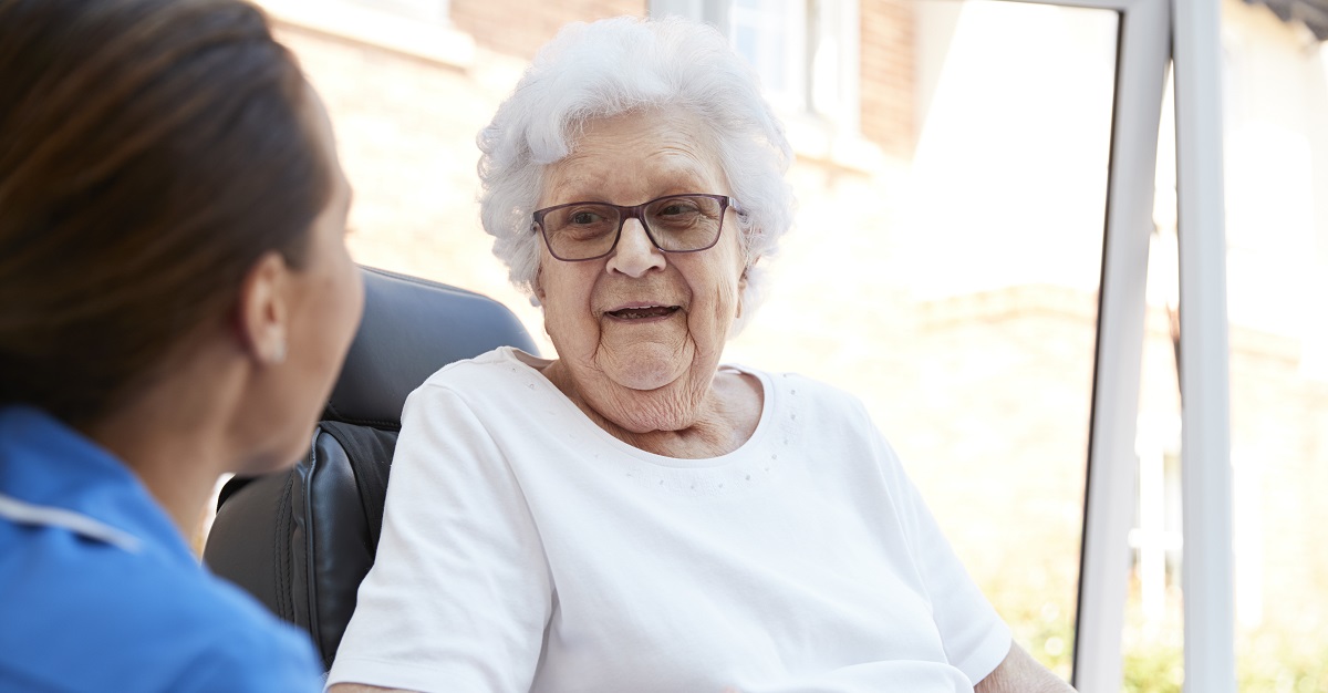 Image shows care home resident talking to a member of staff