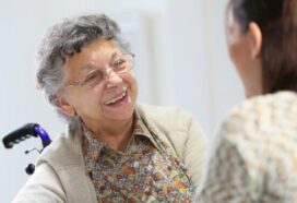 Image shows elderly woman in a wheelchair talking to a care coordinator