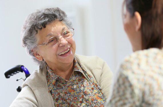 Image shows elderly woman in a wheelchair talking to a care coordinator