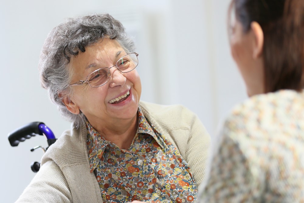 Image shows elderly woman in a wheelchair talking to a care coordinator