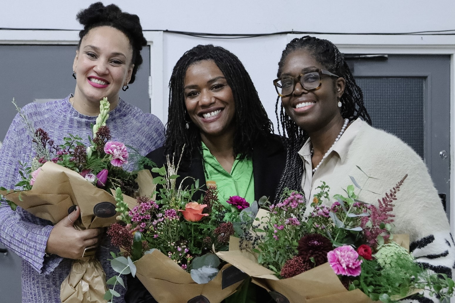 Katie, Sonah and Karen smiling with bouquets of flowers